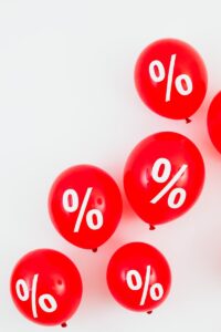 Ballons rouges comportant des symboles de pourcentage pour les ventes et les remises sur fond blanc.
