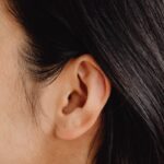 Image détaillée en gros plan présentant une oreille humaine et des cheveux foncés.
