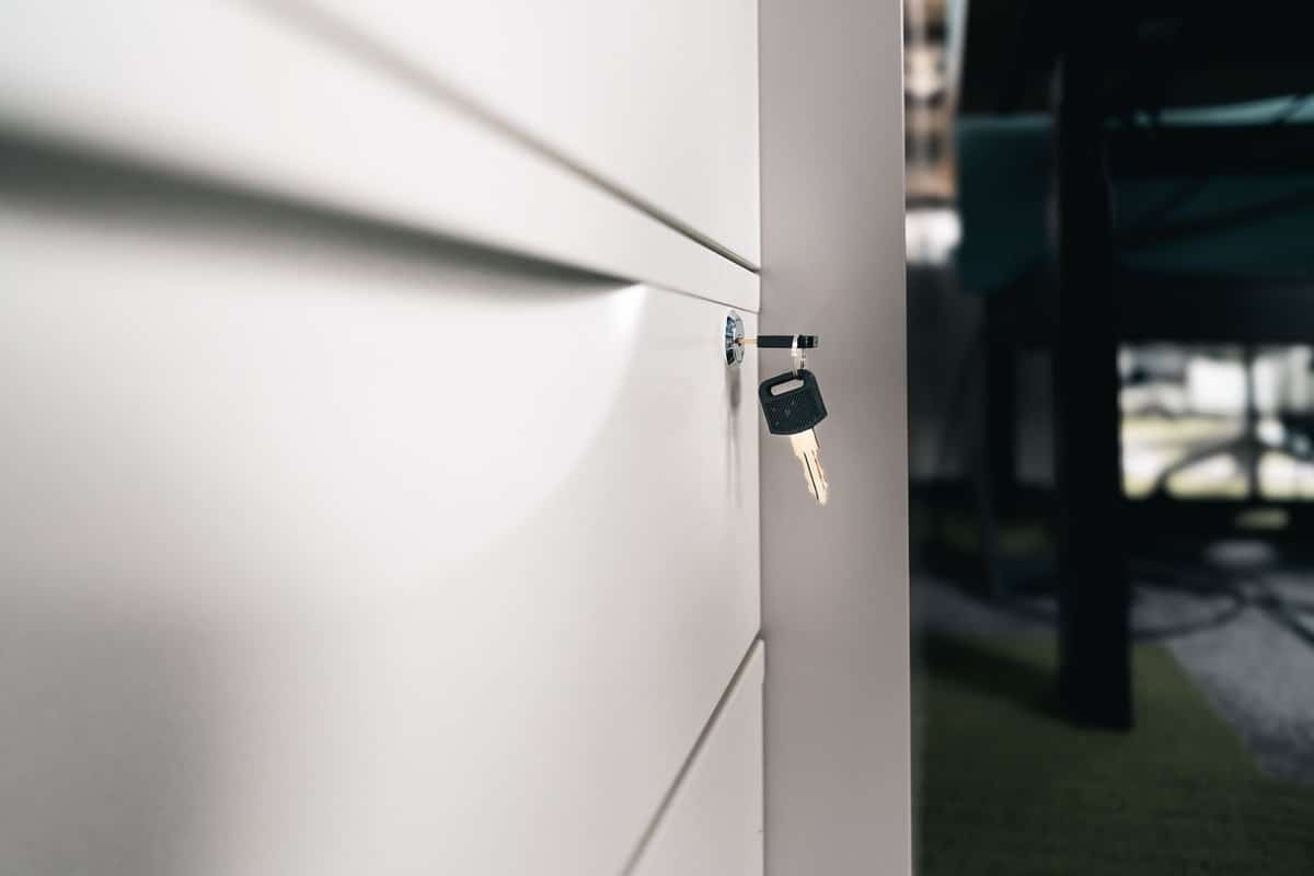 Clé sur une serrure d'un meuble blanc, bureau et chaise visibles
