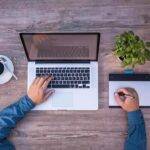 Une personne travaille sur ordinateur portable et utilise une tablette graphique