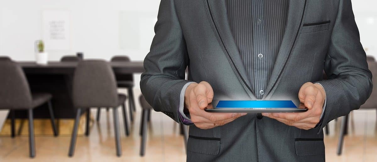 Un homme en costume tenant une tablette dans une salle de réunion