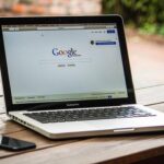 Un ordinateur portable affichant Google, posé sur un banc en bois à l'extérieur