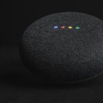 Une enceinte ronde en tissu noir avec quatre LED colorées allumées