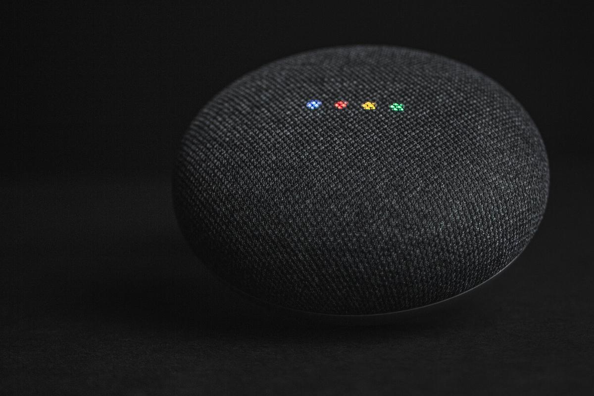Une enceinte ronde en tissu noir avec quatre LED colorées allumées