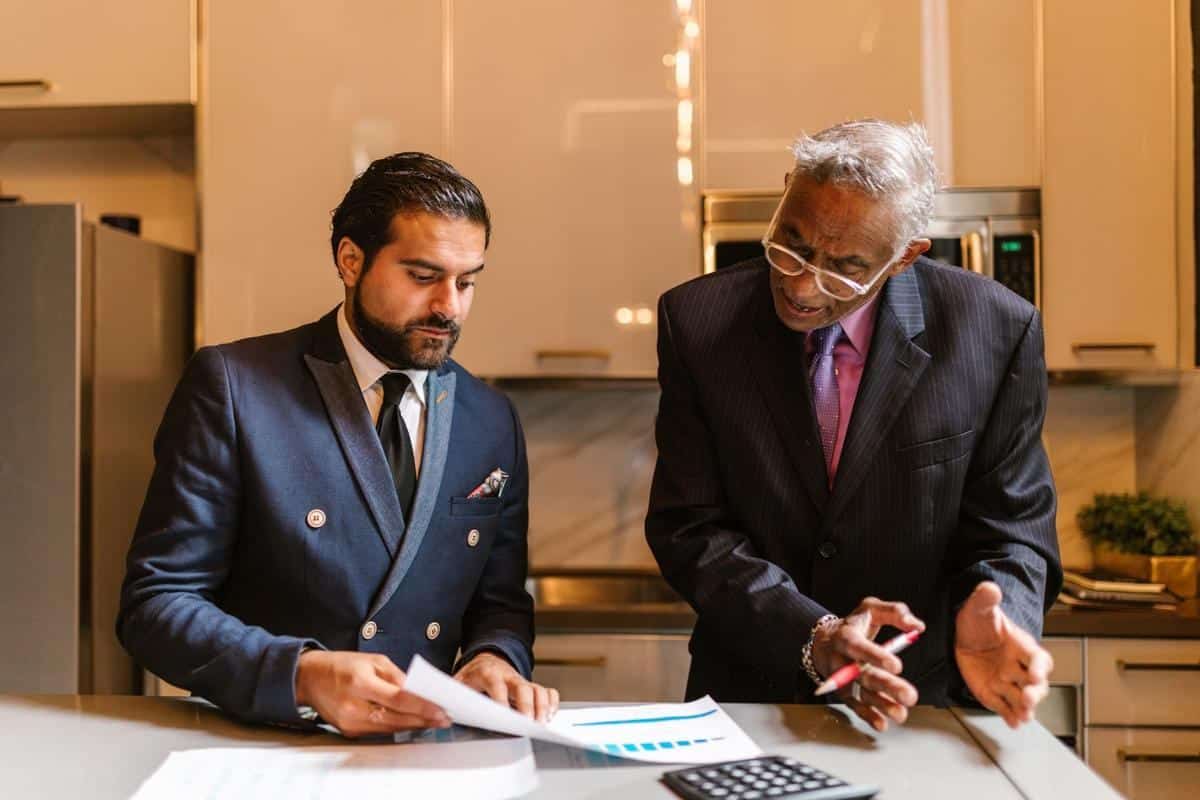 Deux dirigeants en costume examinent des documents à un bureau dans un bureau moderne