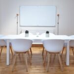 Une salle minimaliste avec table chaises tableau blanc et deux vases