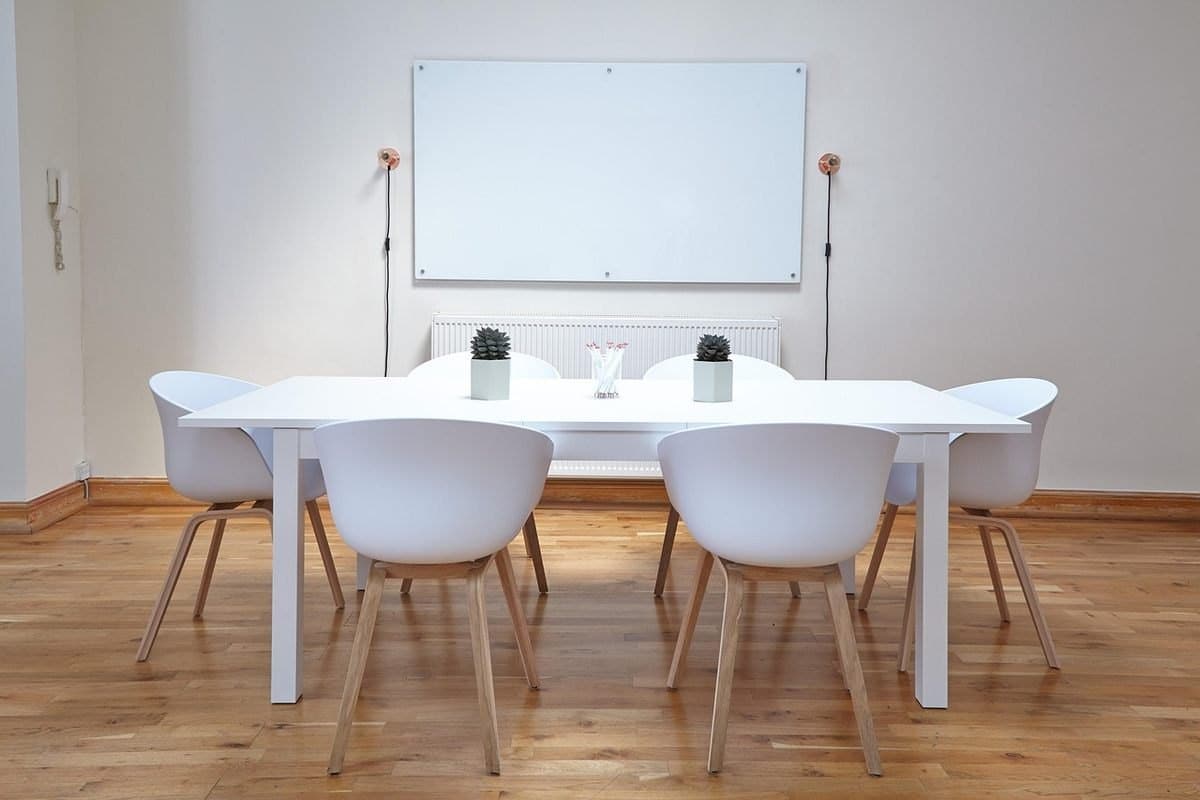 Une salle minimaliste avec table chaises tableau blanc et deux vases