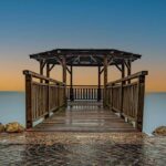 Banc de bois menant à un kiosque au bord d'une mer calme